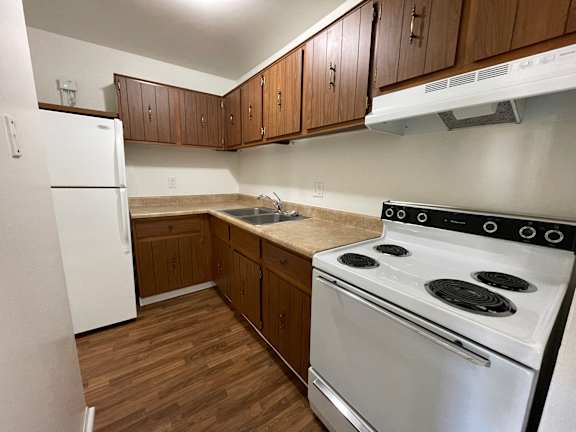 A kitchen with a white stove and wooden cabinets.