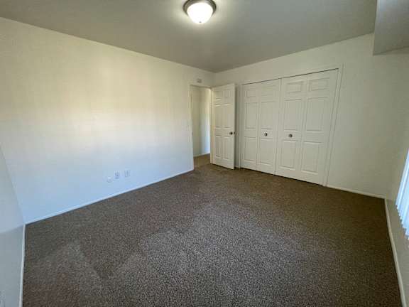 A bedroom with a carpeted floor and a white door.