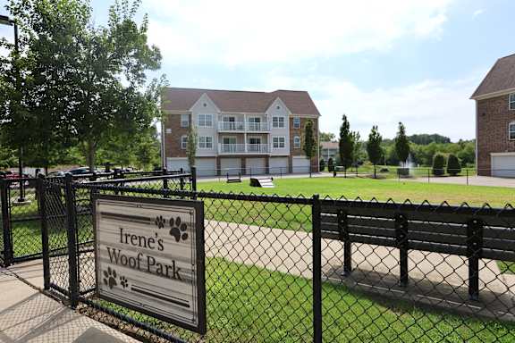 A sign that says Irene's Woof Park is in front of a black fence.