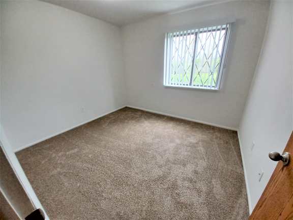 Small carpeted bedroom with security window at Charter Oaks Apartments, Davison, 48423