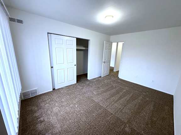 Bedroom with walk-in closet and hallway access at Charter Oaks Apartments, Michigan, 48423