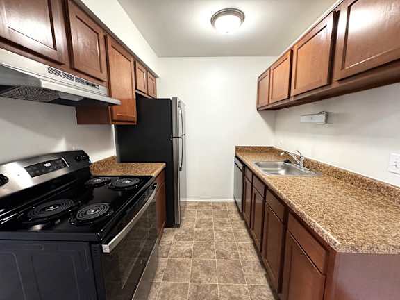 Galley kitchen with granite countertops and black appliances at Charter Oaks Apartments, Michigan