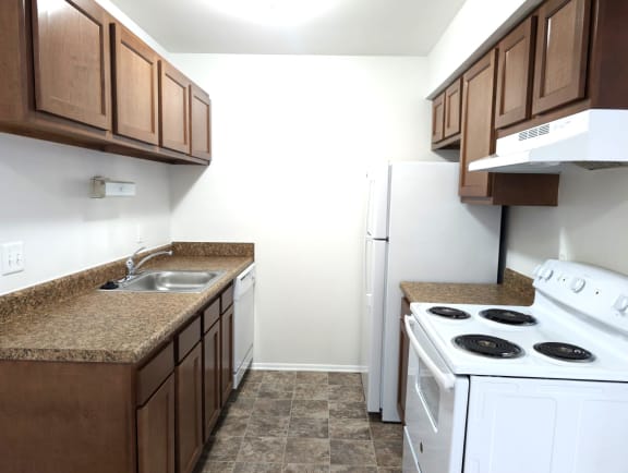 Compact kitchen with white appliances and granite counters at Charter Oaks Apartments, Michigan