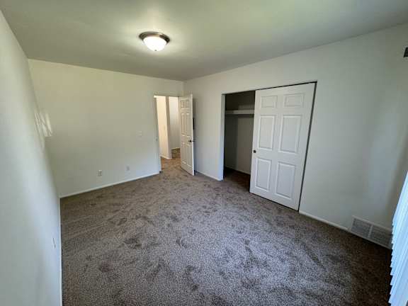 Empty carpeted bedroom with open closet door at Charter Oaks Apartments, Davison, Michigan