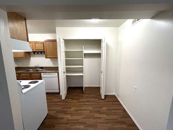 A kitchen with a white fridge and wooden floors.