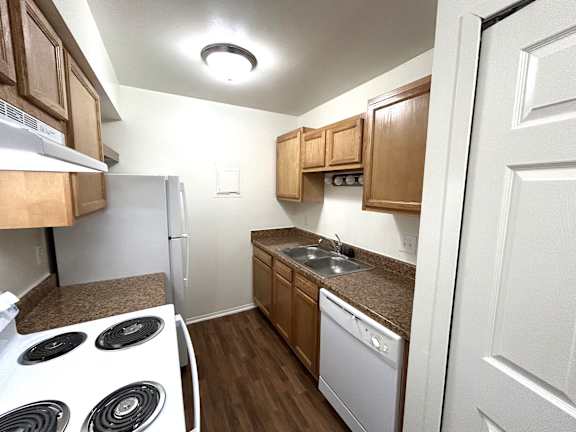 A kitchen with a white fridge, white stove, and brown cabinets.