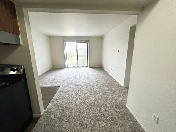 A living room with a carpeted floor and a window with blinds.