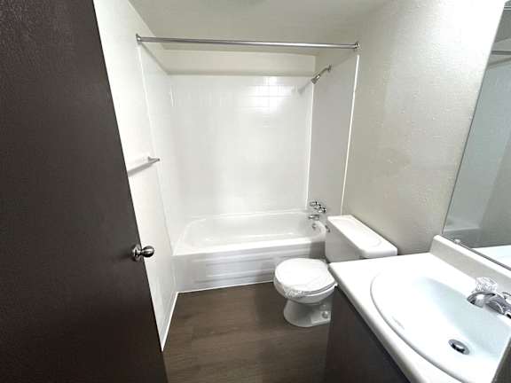 A white toilet sits in a bathroom with a white bathtub and a sink.