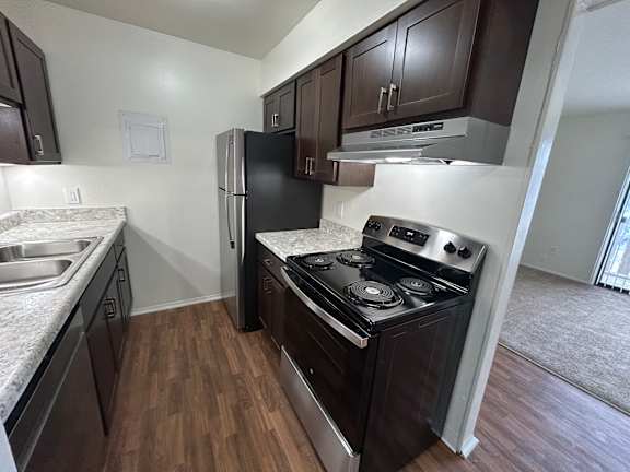 A kitchen with dark wood cabinets and a black stove top oven.