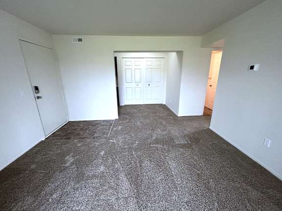 A living room with a carpeted floor and a door in the middle.