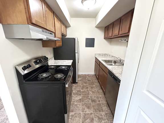 A kitchen with black appliances and brown cabinets.