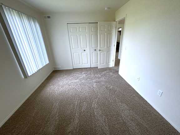 A bedroom with a carpeted floor and a white door.