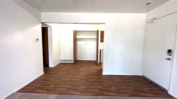 A dining room with a white door and a brown floor.