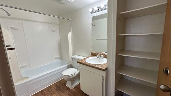 A white bathroom with a toilet, sink, and shelves.