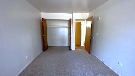 A bedroom with a carpet floor and white walls.