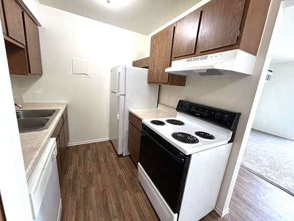 A kitchen with a white stove top oven and white refrigerator.