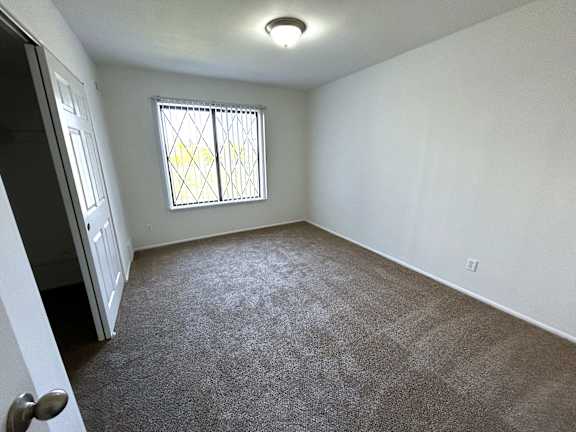 Empty carpeted bedroom with window security bars 1 at Charter Oaks Apartments, Michigan