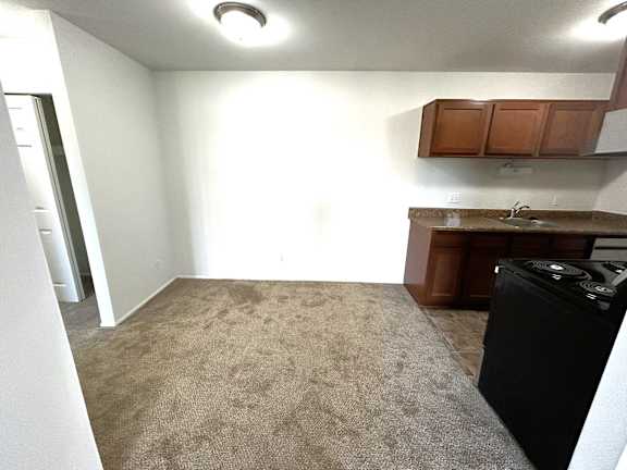 Open kitchen with brown cabinets and black stove at Charter Oaks Apartments, Michigan