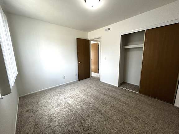 A bedroom with carpeted floor and two doors.