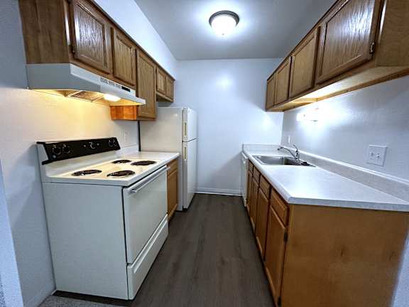 A kitchen with a white fridge and a black stove top.