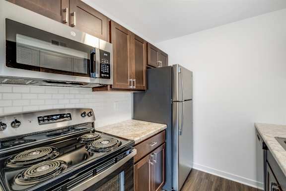 A kitchen with a stove, microwave, and refrigerator.
