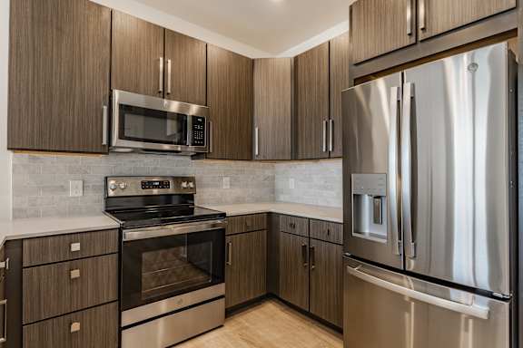 A modern kitchen with a stainless steel refrigerator and wooden cabinets