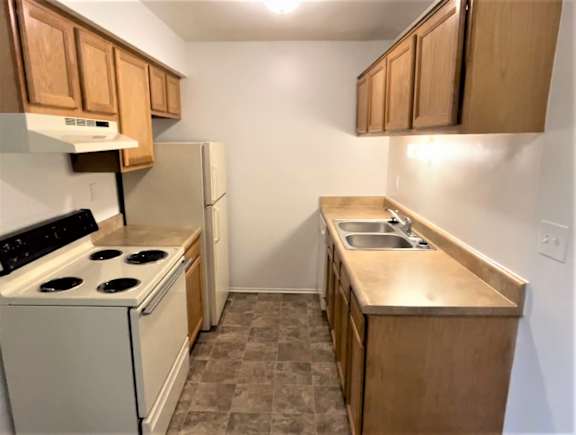 A kitchen with a white stove and a white refrigerator.