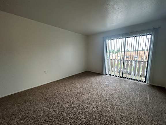 A living room with a carpeted floor and a window with bars.