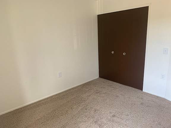A bedroom with a brown door and carpeted floor.