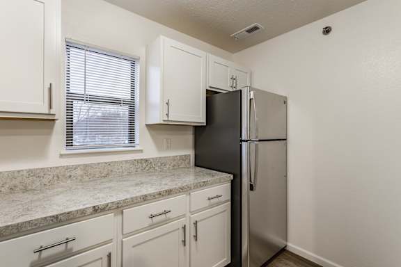 A kitchen with a black refrigerator and white cabinets