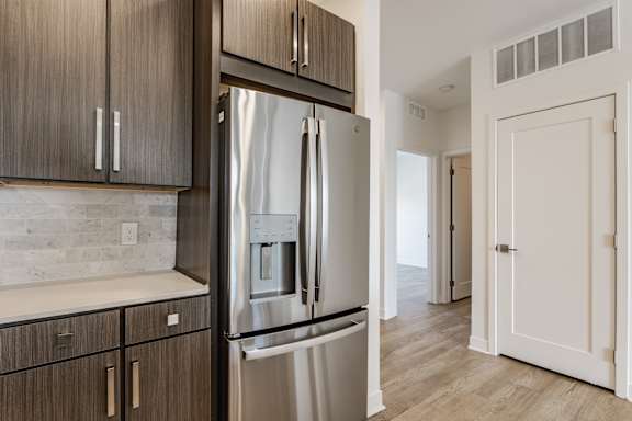 A modern kitchen with a stainless steel refrigerator and wooden cabinets
