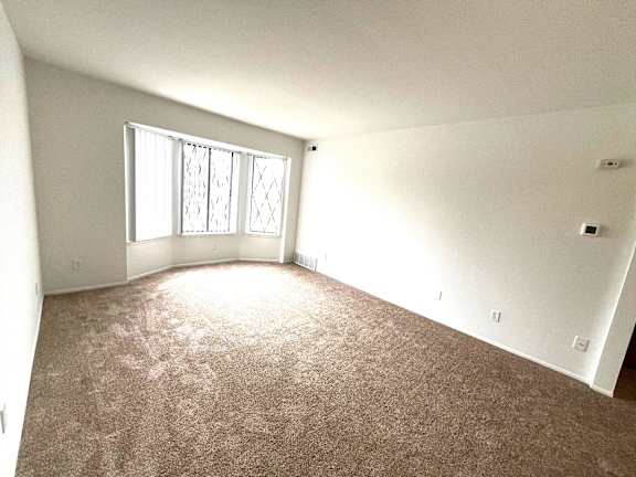 Bright empty room with carpet and bay window at Charter Oaks Apartments, Davison, Michigan