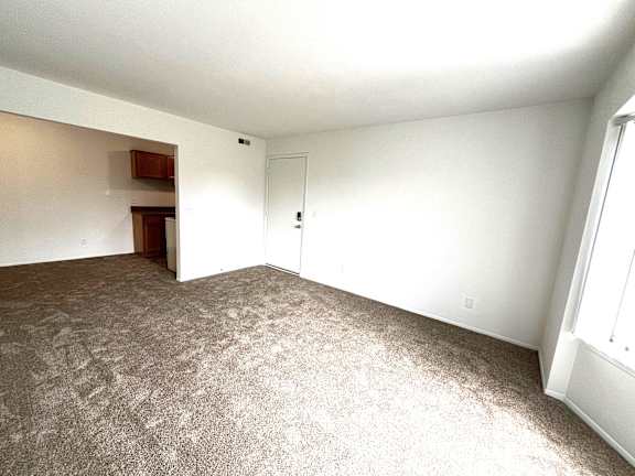 Spacious carpeted living area with entry door 1 at Charter Oaks Apartments, Michigan, 48423