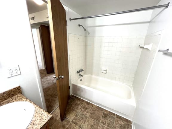 Bathroom with white tiled tub and shower curtain rod at Charter Oaks Apartments, Davison, 48423