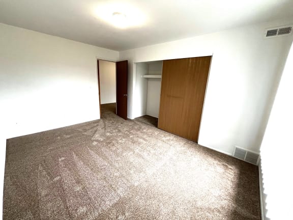 Empty carpeted bedroom with open closet and doorway 1 at Charter Oaks Apartments, Davison, Michigan