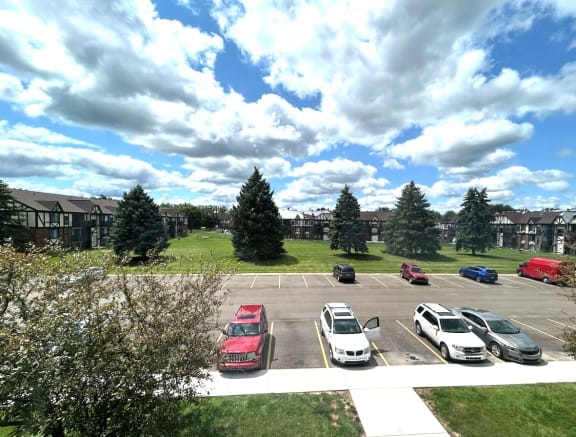 Parking lot with green lawn and evergreen trees at Charter Oaks Apartments, Davison, Michigan