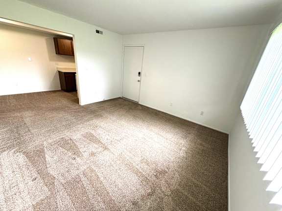Spacious carpeted living area with entry door at Charter Oaks Apartments, Michigan, 48423