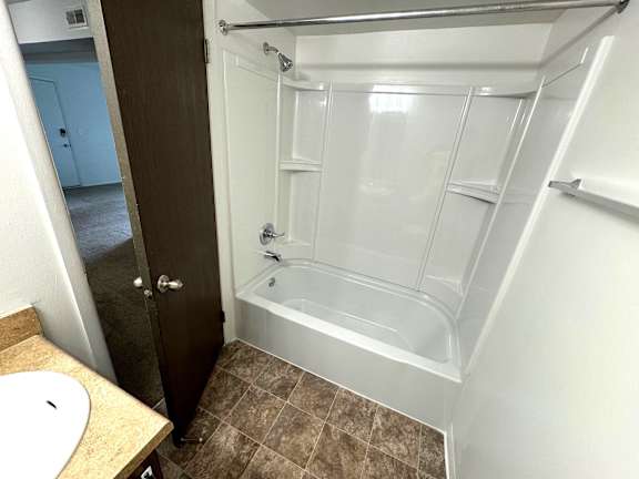 Bathroom with white tub surround and shower rod at Charter Oaks Apartments, Davison