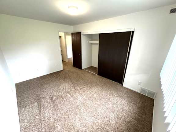 Empty carpeted bedroom with open closet and doorway at Charter Oaks Apartments, Davison, MI, 48423