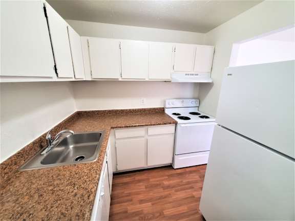 A kitchen with white cabinets and a white refrigerator.