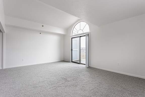 A room with a carpeted floor and a large arched window
