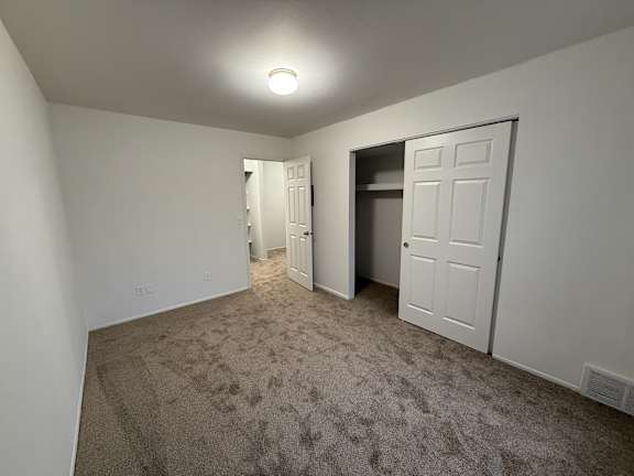 a bedroom with a carpeted floor and a door to a closet