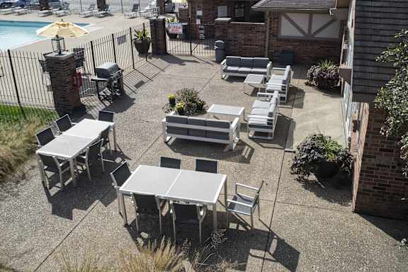 an outdoor patio with tables and chairs and a pool at The Timbers Apartments, Evansville