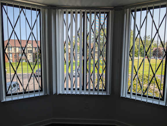 Bay window with vertical blinds and crisscross security bars at Charter Oaks Apartments, Michigan, 48423