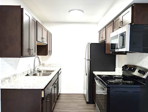 Galley kitchen with white subway tile backsplash at Charter Oaks Apartments, Michigan, 48423