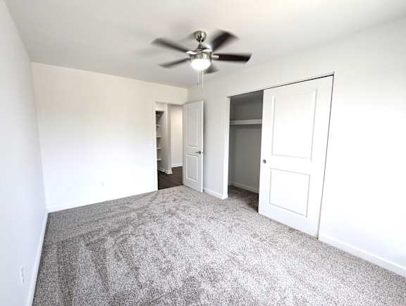 Empty carpeted bedroom with closet and ceiling fan at Charter Oaks Apartments, Michigan, 48423