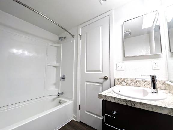 Modern bathroom with granite vanity and tub shower combo at Charter Oaks Apartments, Michigan