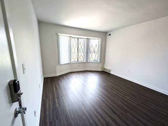 Spacious empty living room with bay window and laminate flooring at Charter Oaks Apartments, Davison, 48423