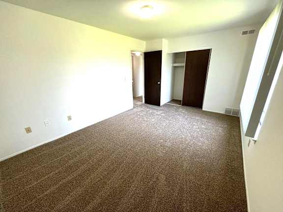 Empty carpeted bedroom with closet and doorway at Charter Oaks Apartments, Davison