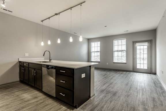 an empty living room with an island in the center of it and a large kitchen at Bella Vista Apartments, Fishers
